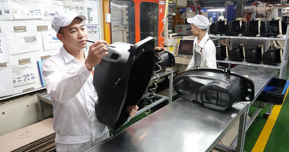 Nhân viên kiểm tra vỏ nhựa màu đen tại bàn thao tác của dây chuyền