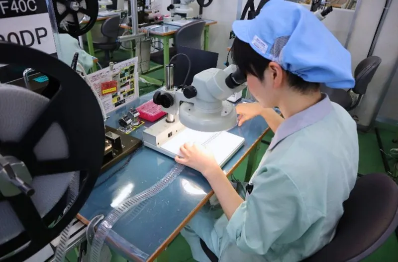 Nhân viên quan sát chi tiết nhựa bằng kính hiển vi tại trạm kiểm tra