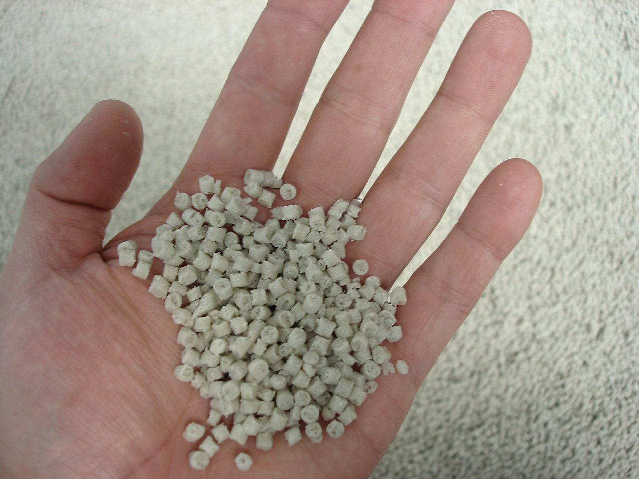 Hạt polymer màu sáng trên lòng bàn tay, dạng nguyên liệu dùng làm vật liệu ép nhựa